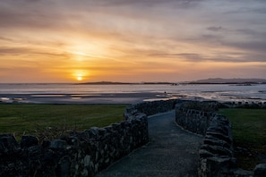 Walk through the historic stone wall to a serene coastal scene.