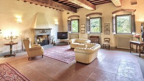 A spacious living room with a fireplace, comfortable seating, and large windows. - VILLA FIESOLANA - Twelve Bedroom Villa, Sleeps 34 (Pontassieve)