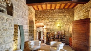 A stone-walled room with two white armchairs, a bookshelf, and a wooden door. - VILLA FIESOLANA - Twelve Bedroom Villa, Sleeps 34 (Pontassieve)