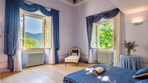 A bedroom with two windows, a bed, a chair, and a small table with a vase. - VILLA FIESOLANA - Twelve Bedroom Villa, Sleeps 34 (Pontassieve)