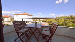 Un balcón con una mesa y dos sillas, con vista a una zona residencial con casas y vegetación.