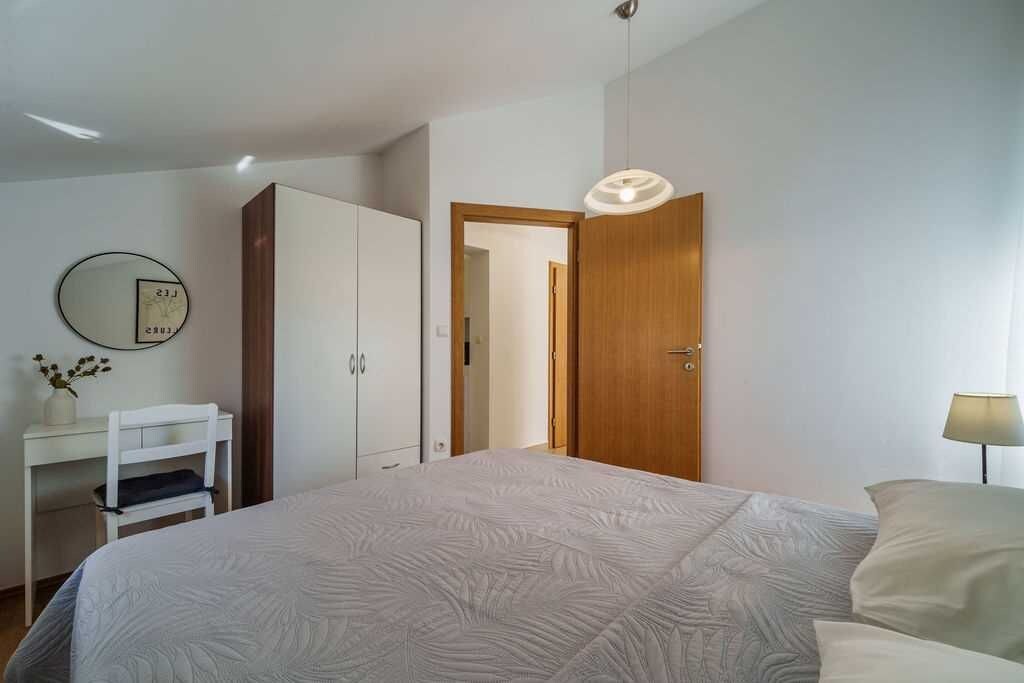 A bedroom with a bed, a desk, a wardrobe, and a door.