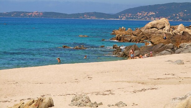 A beach with clear blue water, rocky outcrops, and a distant town. - Olmeto Plage: Large 3-bedroom apartment 200 metres from the sea (Olmeto)
