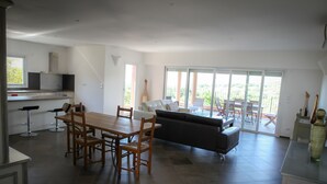 A modern kitchen with a dining area, a sofa, and a balcony with outdoor furniture. - Olmeto Plage: Large 3-bedroom apartment 200 metres from the sea (Olmeto)