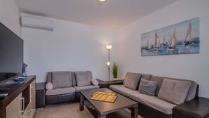 A modern living room with two grey sofas, a wooden coffee table, a floor lamp, and a painting of sailboats on the wall. - Apartment Šop with balcony (Čižići)