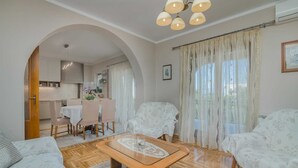 Un salon chaleureux avec une table basse en bois, deux fauteuils à motifs, un canapé et un coin repas comprenant une table et des chaises.