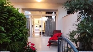 A staircase leading to a balcony with a chair and a red cushion, surrounded by potted plants.