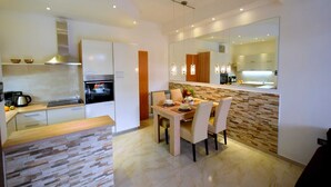 A modern kitchen with a dining area, featuring a stone countertop, a built-in oven, and a large mirror above the counter.