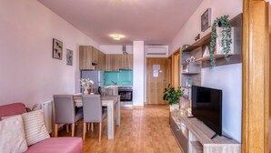 A modern apartment with a dining area, kitchen, living room, and a TV mounted on a wooden shelf. - Apartment Baran with a Sea View (Čižići)