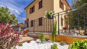 A two-story building with a balcony, white stone pathway, and potted plants. - Apartment Baran with a Sea View (Čižići)