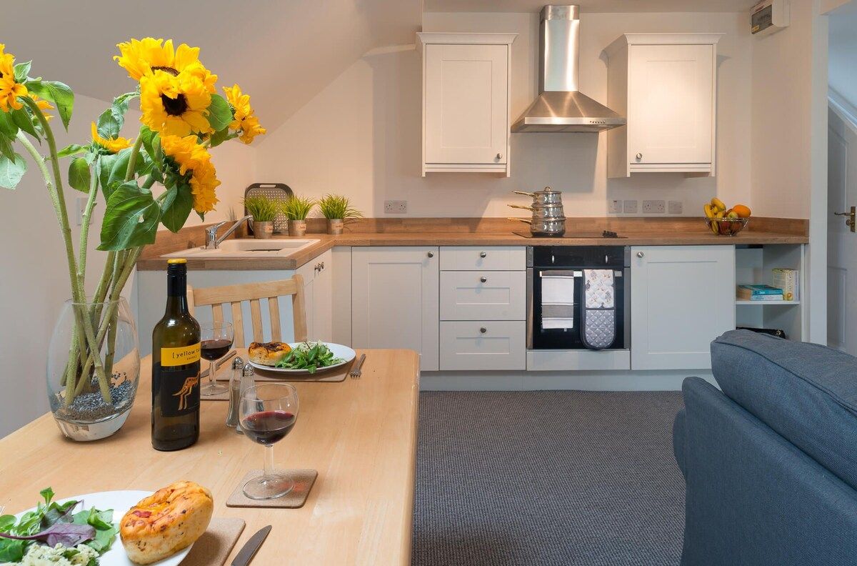 A modern kitchen with white cabinets, a wooden countertop, and a dining area with a table set for a meal.