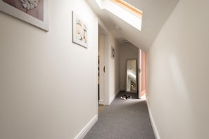 A hallway with a skylight, a door, and a pair of shoes on the floor.