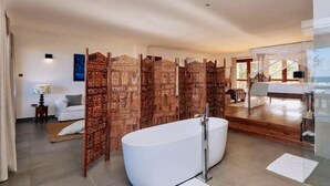 Une salle de bain spacieuse avec une baignoire sur pieds, un grand miroir et une cloison en bois.