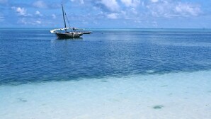 Un bateau est ancré dans des eaux calmes, près du rivage, où l’on trouve des zones peu profondes et aux eaux claires.