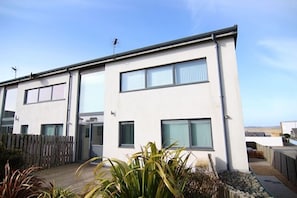 A modern two-story residential building with large windows and a flat roof.