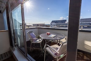 A balcony with a glass door, a round table, and two chairs.