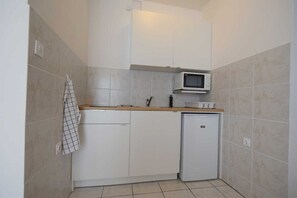 Compact kitchen with modern design, white cabinetry, refrigerator, microwave, and sink.
