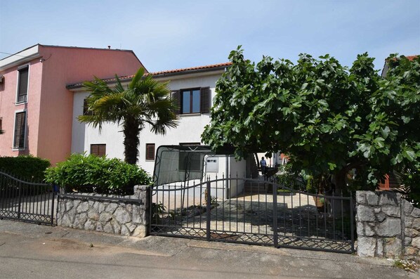 Stunning residential building with a stone wall, metal gate, and lush greenery.