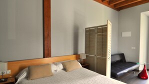 A bedroom with a bed, bedside tables, a wardrobe, and a small seating area. - Rural apartment Casona la Sierra for 3 people (Cudillero)