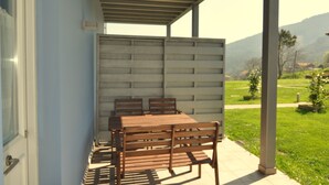 A covered outdoor seating area with a table and chairs, a view of a green landscape with trees and a mountain in the background. - Rural apartment Casona la Sierra for 3 people (Cudillero)