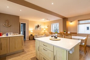 Una cocina moderna con una isla central, armarios de madera y un comedor con mesa y sillas.