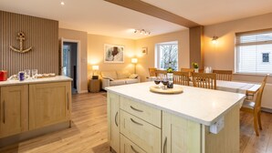 A modern kitchen with wooden cabinets, a central island, and a dining area with a table and chairs.