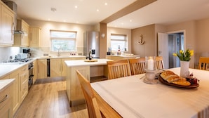 A modern kitchen with wooden cabinets, a central island, and a dining area with a table set for two.