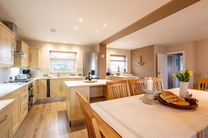 Una cocina moderna con armarios de madera, una isla central y un comedor con mesa para dos.