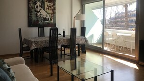 A dining area with a glass table, chairs, and a painting on the wall. - BEACH APARTMENT 3 in TOSSA DE MAR (Tossa de Mar)