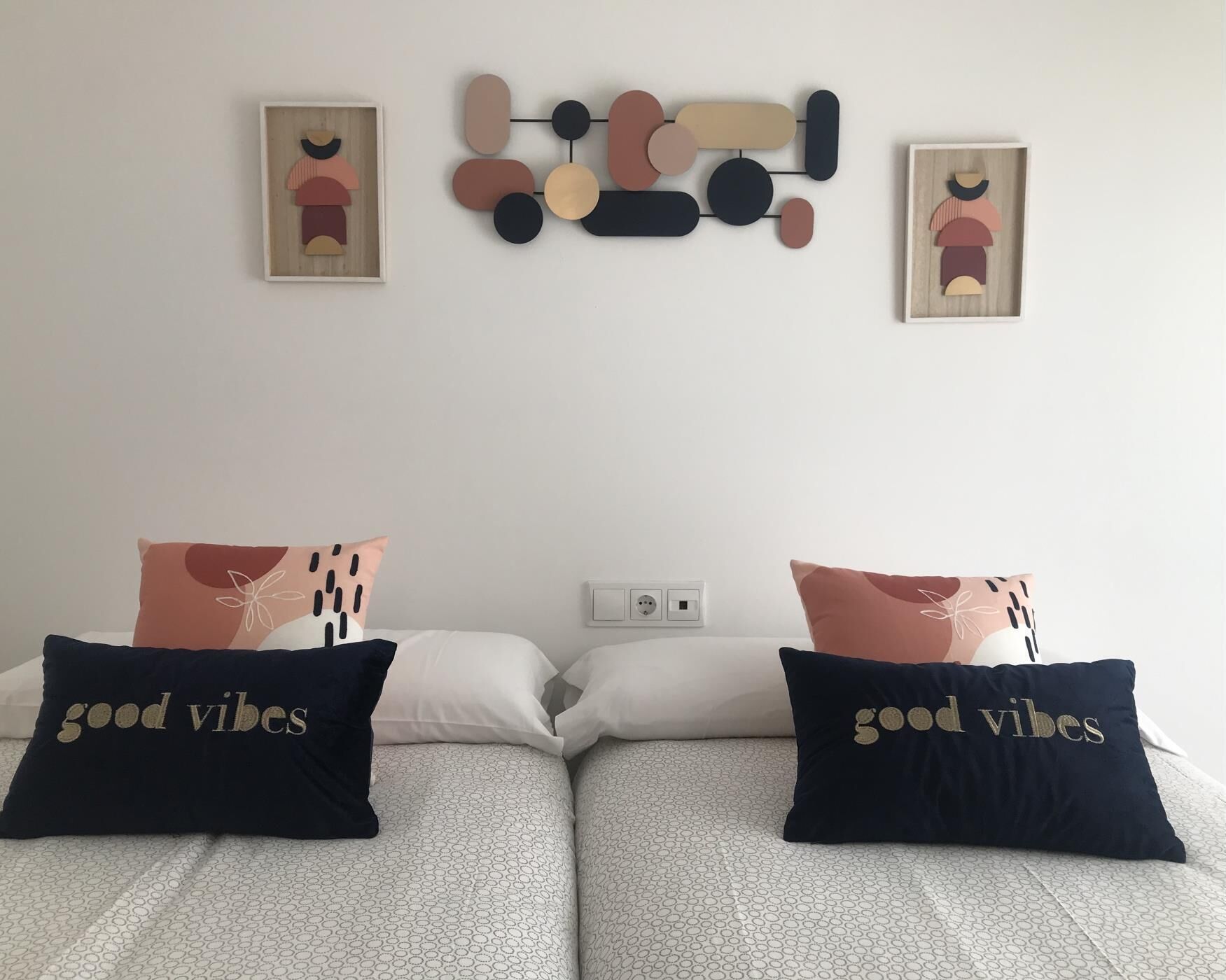 A double bed with two pillows, a wall art piece, and a power outlet.