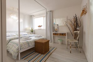 A bedroom with a bed, bedside table, lamp, and a small plant.