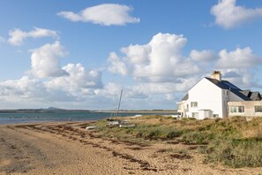 A coastal property with a white house, sandy beach, and boats.