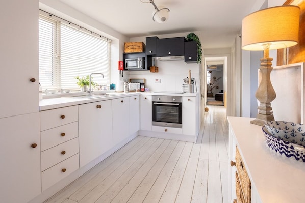 A modern kitchen with white cabinetry, a built-in oven, and a microwave.