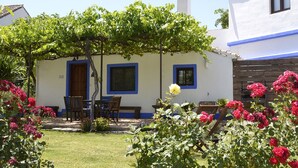 A white building with blue trim and windows, a covered patio area, and a garden with roses. - Self catering Cortijo Algabia for 4 people (Alhendín)