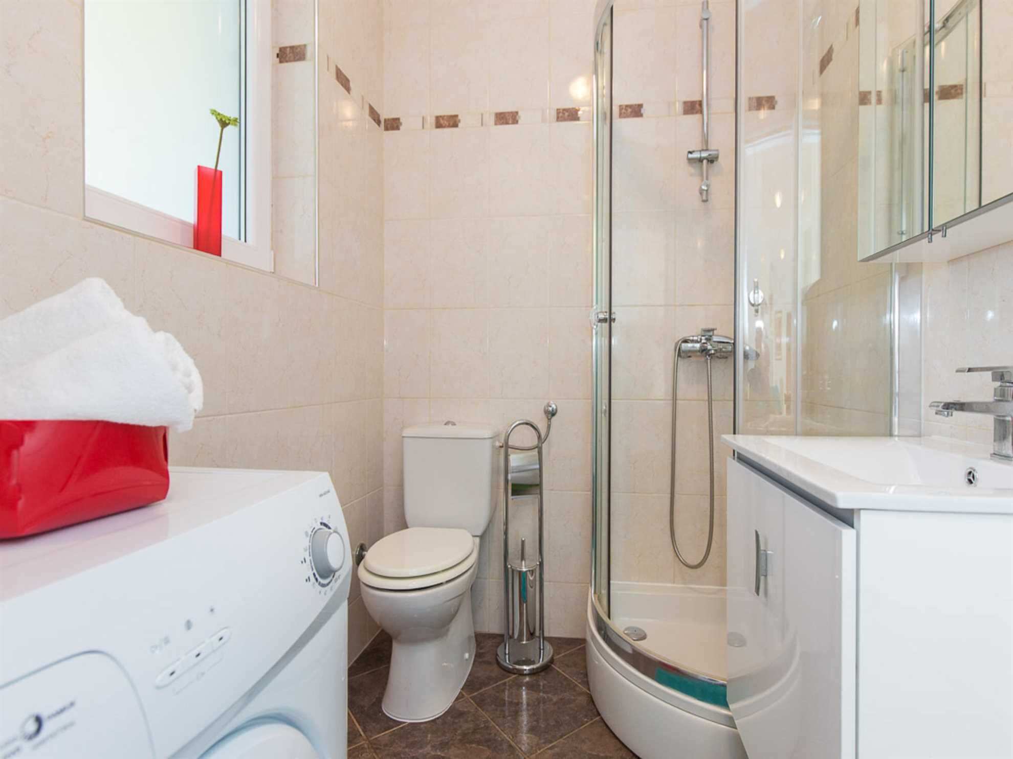 A modern bathroom with a toilet, a glass-enclosed shower, and a white sink.