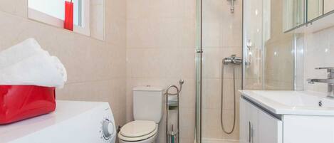 A modern bathroom with a toilet, a glass-enclosed shower, and a white sink.