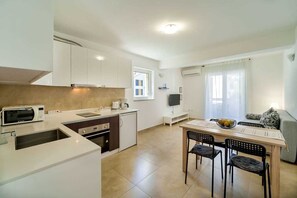 Une cuisine moderne avec des meubles blancs, un four à micro-ondes et un coin repas comprenant une table et des chaises.