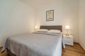 Une chambre à coucher avec un lit, deux tables de chevet et une lampe fixée au mur.