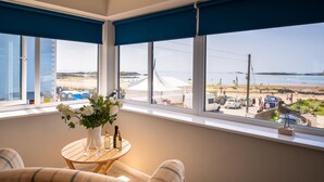 Ein Zimmer mit Meerblick, ein kleiner Tisch mit Blumen in einer Vase und ein Sofa.