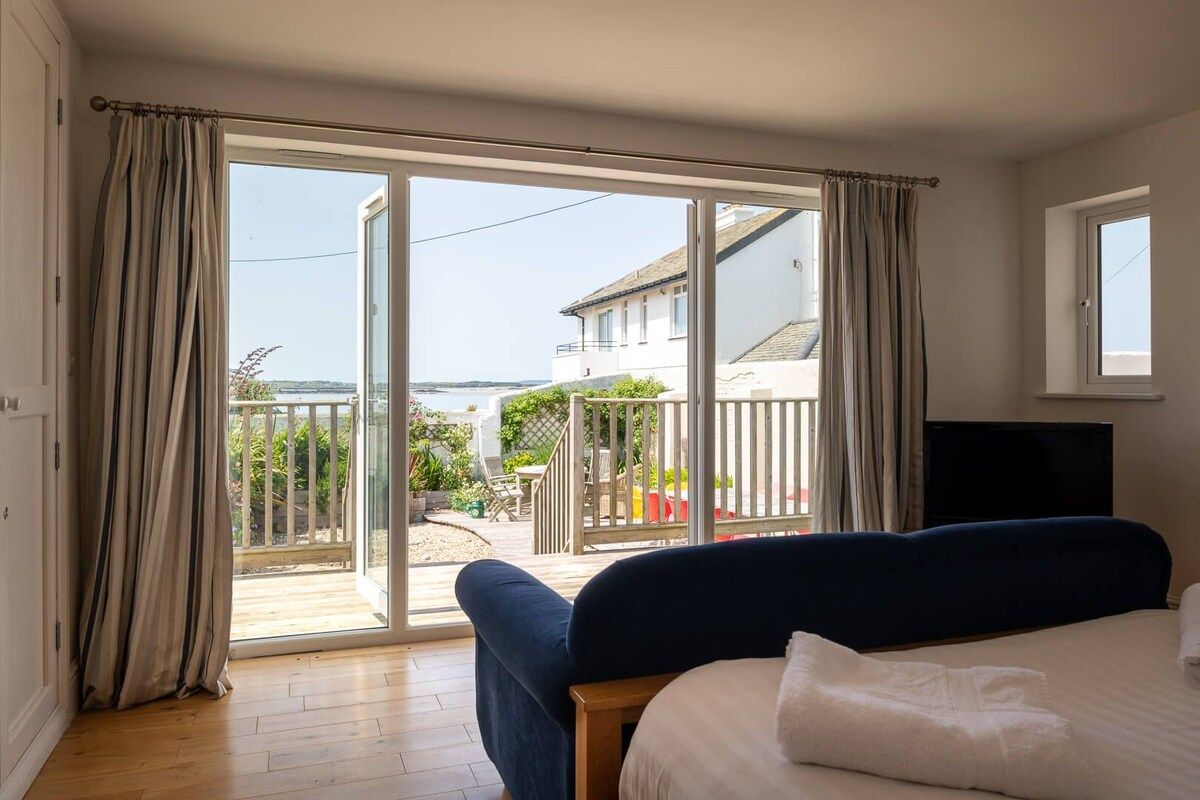 A bedroom with a large sliding glass door leading to a balcony, a bed, and a television.