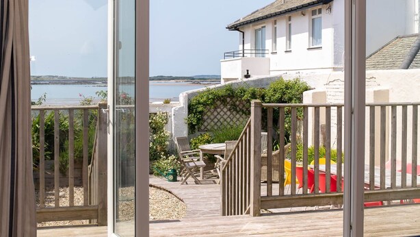 Ein Küstenanwesen mit einer Holzterrasse, Sitzgelegenheiten im Freien und Blick aufs Meer.