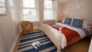 A bedroom with a bed, a chair, a star decoration, and a tray with a teapot and cups. - Bryn Awel: Family-Friendly 3-Bed Apartment in Rhosneigr | Managed by Anglesey Holiday Lettings (Rhosneigr)
