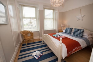 A bedroom with a bed, a chair, a star decoration, and a tray with cups and saucers. - Bryn Awel: A three bed flat in Rhosneigr with sea views (Rhosneigr)