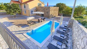 Une maison avec une piscine, des murs en pierre et du mobilier d’extérieur.