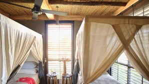 Una stanza con due letti, un ventilatore a soffitto e un piccolo tavolo con sedie.