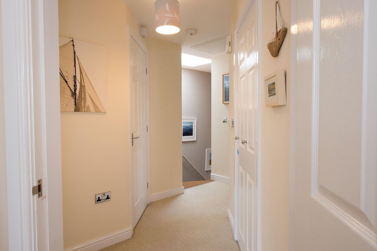 A hallway with white doors, a light fixture, and a wall-mounted picture.