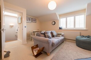 A cozy living room with a sofa, a bean bag, a small table, and a radiator.