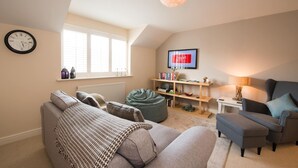 A cozy living room with a sofa, a bean bag, a television, and a bookshelf. - Bryns Eglwys: Pet-friendly two bed holiday apartment in Rhosneigr (Rhosneigr)