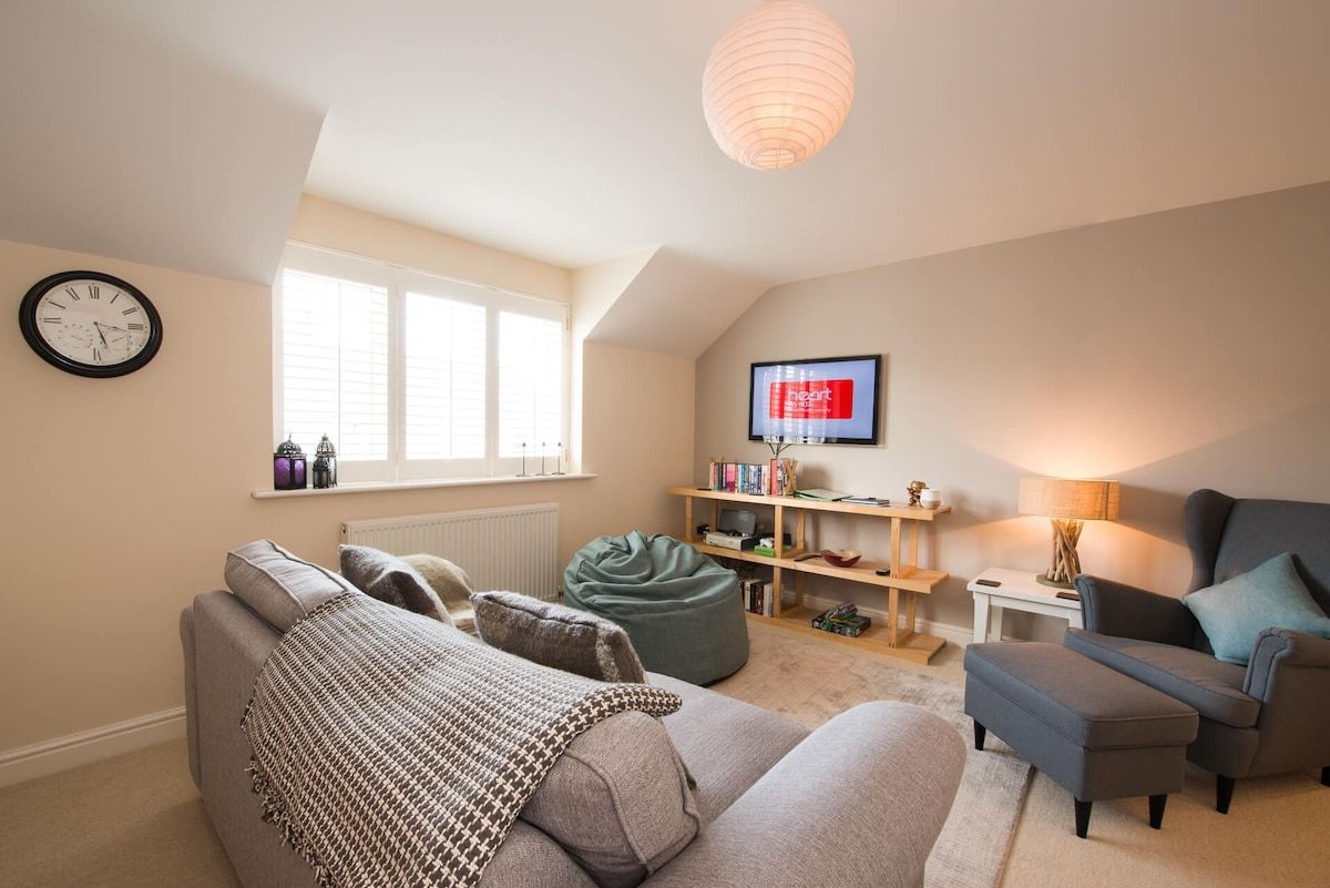 A cozy living room with a sofa, a bean bag, a television, and a bookshelf.