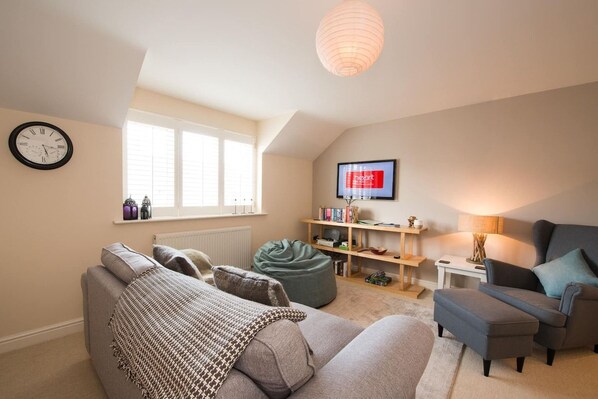 A cozy living room with a sofa, a bean bag, a television, and a bookshelf.